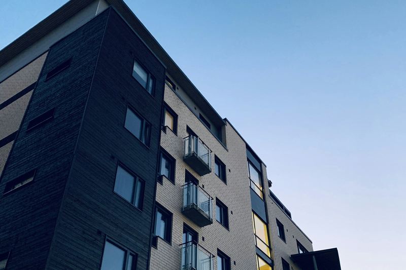 Fachada de edifício residencial moderno em revestimento escuro, vista de baixo contra o céu.